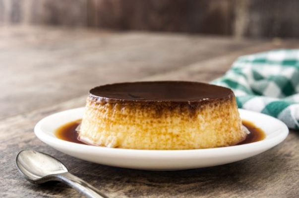 Vanilla bean flan on a plate with a spoon Vanilla bean flan on a plate with a spoon