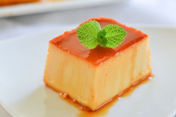 Slice of Leche Flan on a plate with a mint leaf